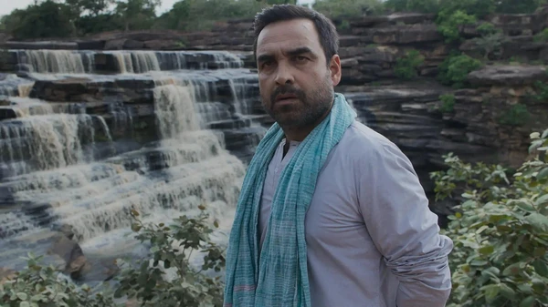 A man stands by a waterfall, looking serious in "Mirzapur".