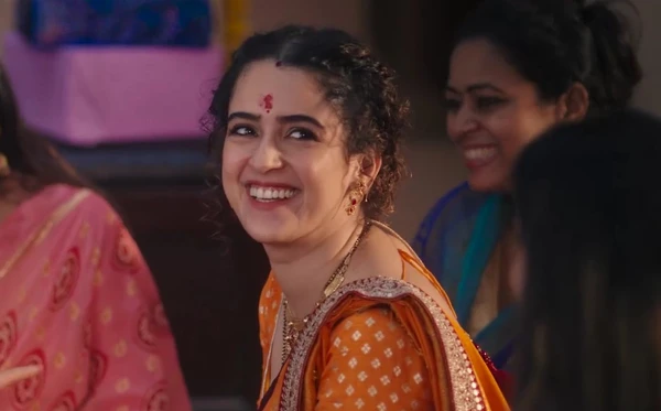 A woman smiles among others in a social setting in the movie "Mrs".