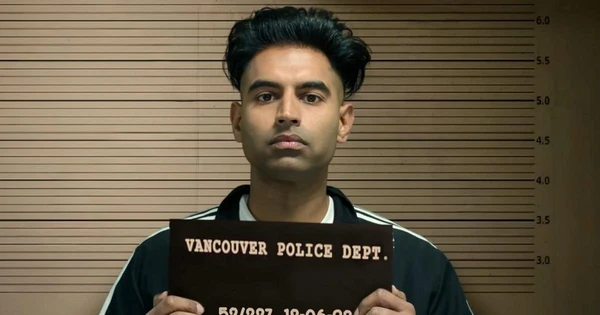 Character holds a police mugshot board in "Kanneda", set against a law - enforcement backdrop.