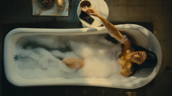 A woman relaxing in a bubble - filled bathtub in Mandala Murders.（