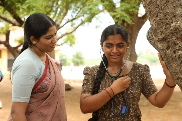 A girl wearing a stethoscope smiles, showing her doctor dream in Ayali, beside a woman.