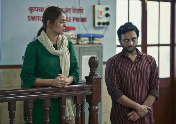 Two characters stand near a railing in what seems to be a police - station - like setting in Criminal Justice: A Family Matter.
